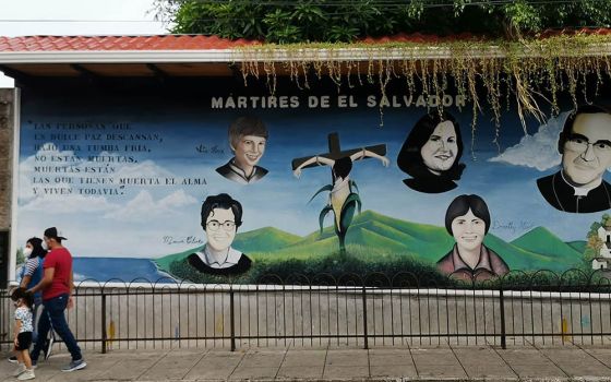 Salvadorans walk past a mural of Salvadoran martyrs Aug. 15, 2020, outside Our Lady of Pilar Catholic Church in Zaragoza, El Salvador. The mural includes St. Óscar Romero and four U.S. churchwomen slain in El Salvador in 1980. (CNS)